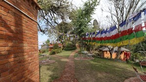 Un edificio de ladrillo con un camino empedrado que lleva a un jardín con mesas y sillas.