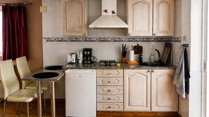 Cozinha compacta com área de refeições, equipada com geladeira, cafeteira e pia.