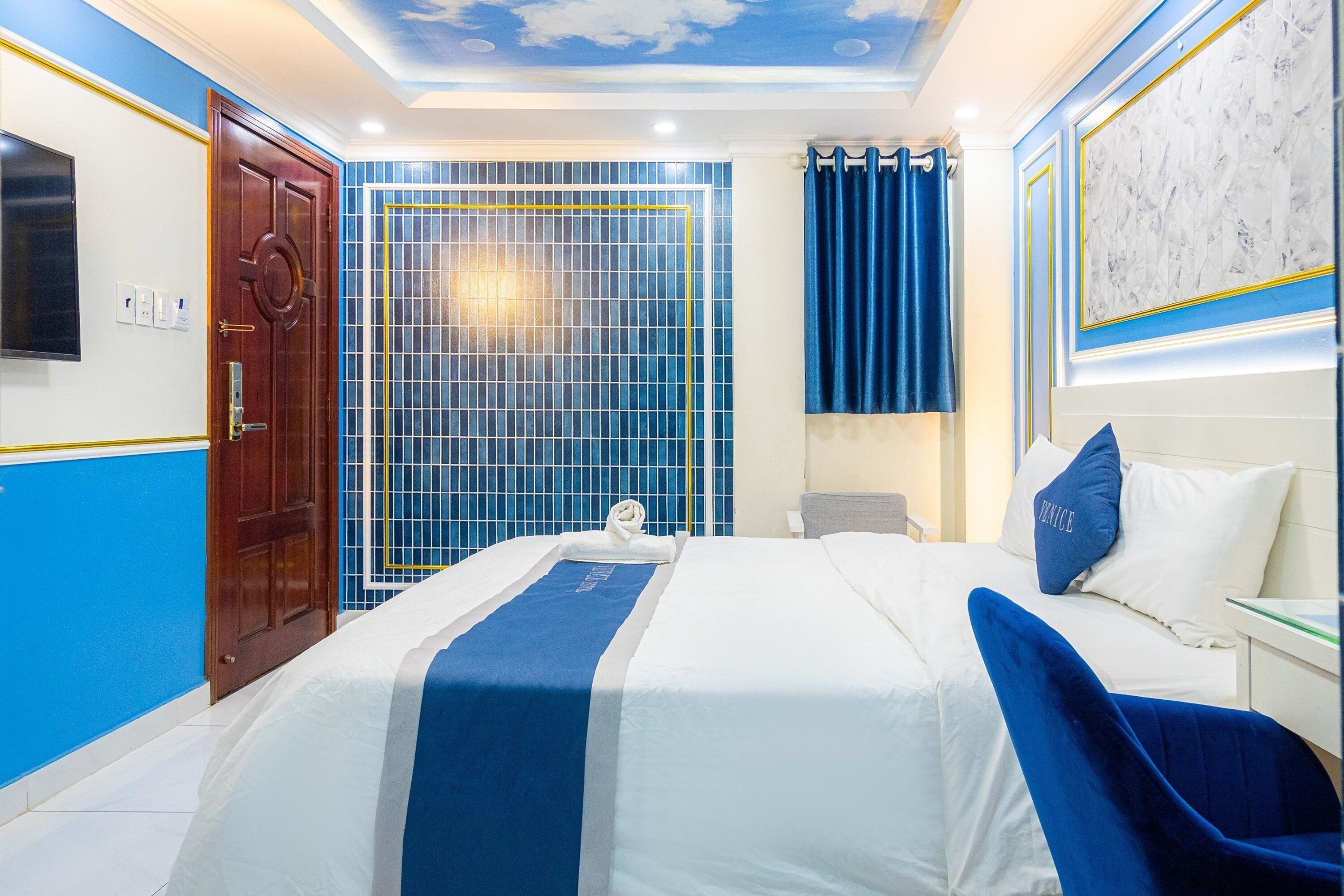A hotel room with a bed, a desk, a TV, and a bathroom with a shower curtain.