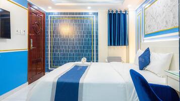 A hotel room with a bed, a desk, a TV, and a bathroom with a shower curtain.