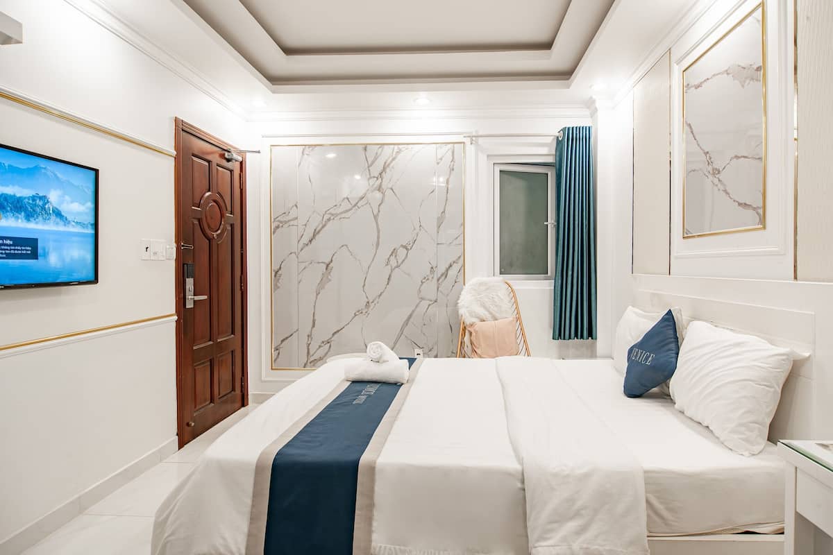 Une chambre d’hôtel avec un lit, une télévision, une porte et des murs en marbre.