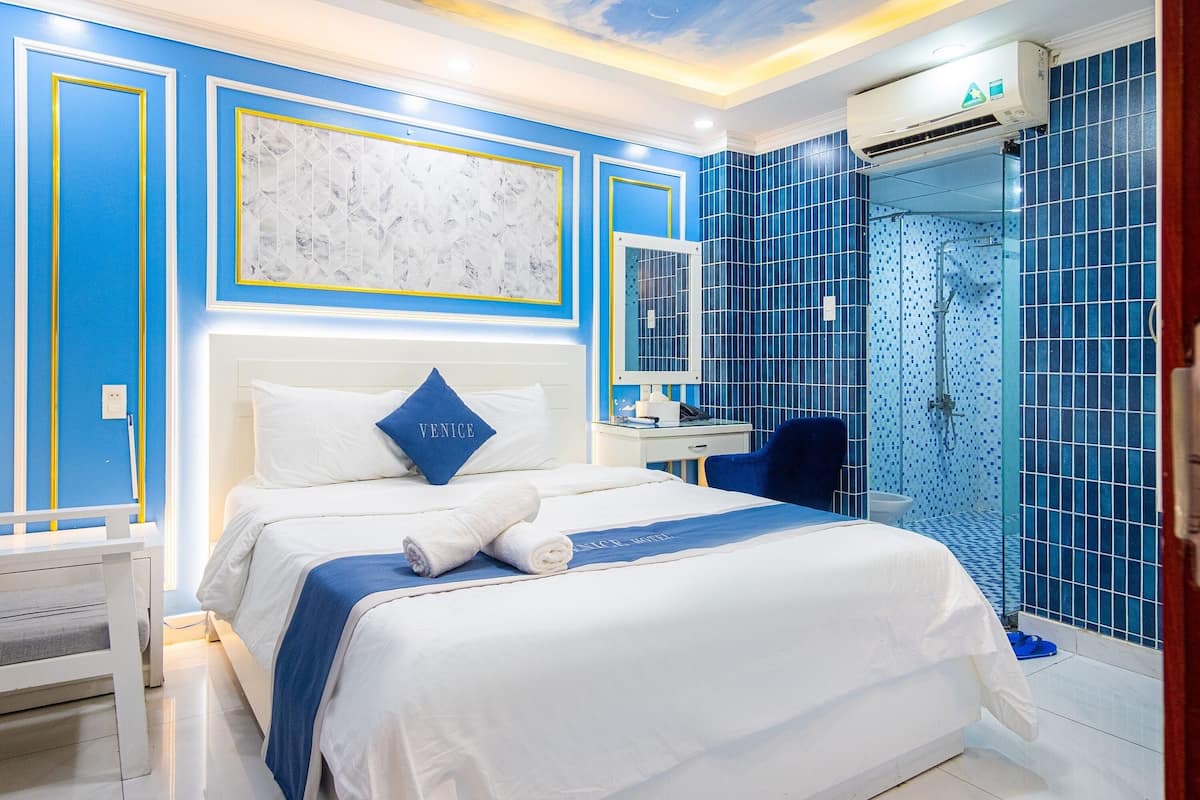 Une chambre d’hôtel comprenant un lit, une table de chevet, un bureau et un espace douche.