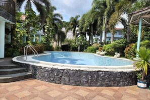 A swimming pool surrounded by stone walls, palm trees, and a gazebo. - Villa Celine Bay Laguna (Bay)