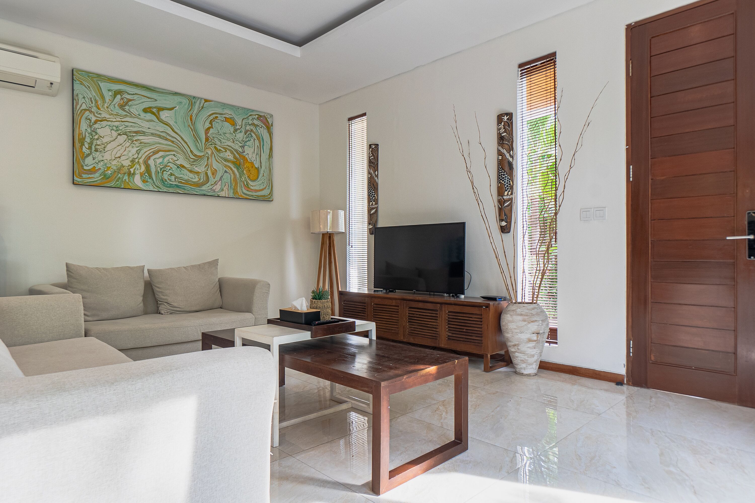 Una sala de estar moderna con sofá, mesa de centro, televisor y elementos decorativos.