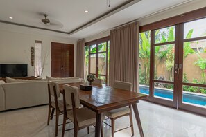 A spacious living area with a dining table, chairs, a sofa, and a television. - Miles Villa (Nusa Dua)