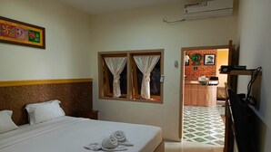A hotel room with a bed, a window with curtains, a wall-mounted air conditioner, and a framed picture. - Adisa Homestay (Malang)