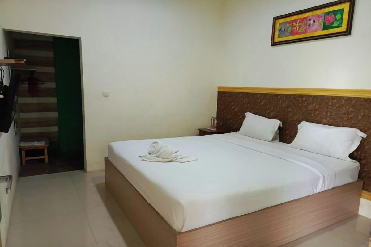 A neatly made bed with white linens and a folded towel on the bed.