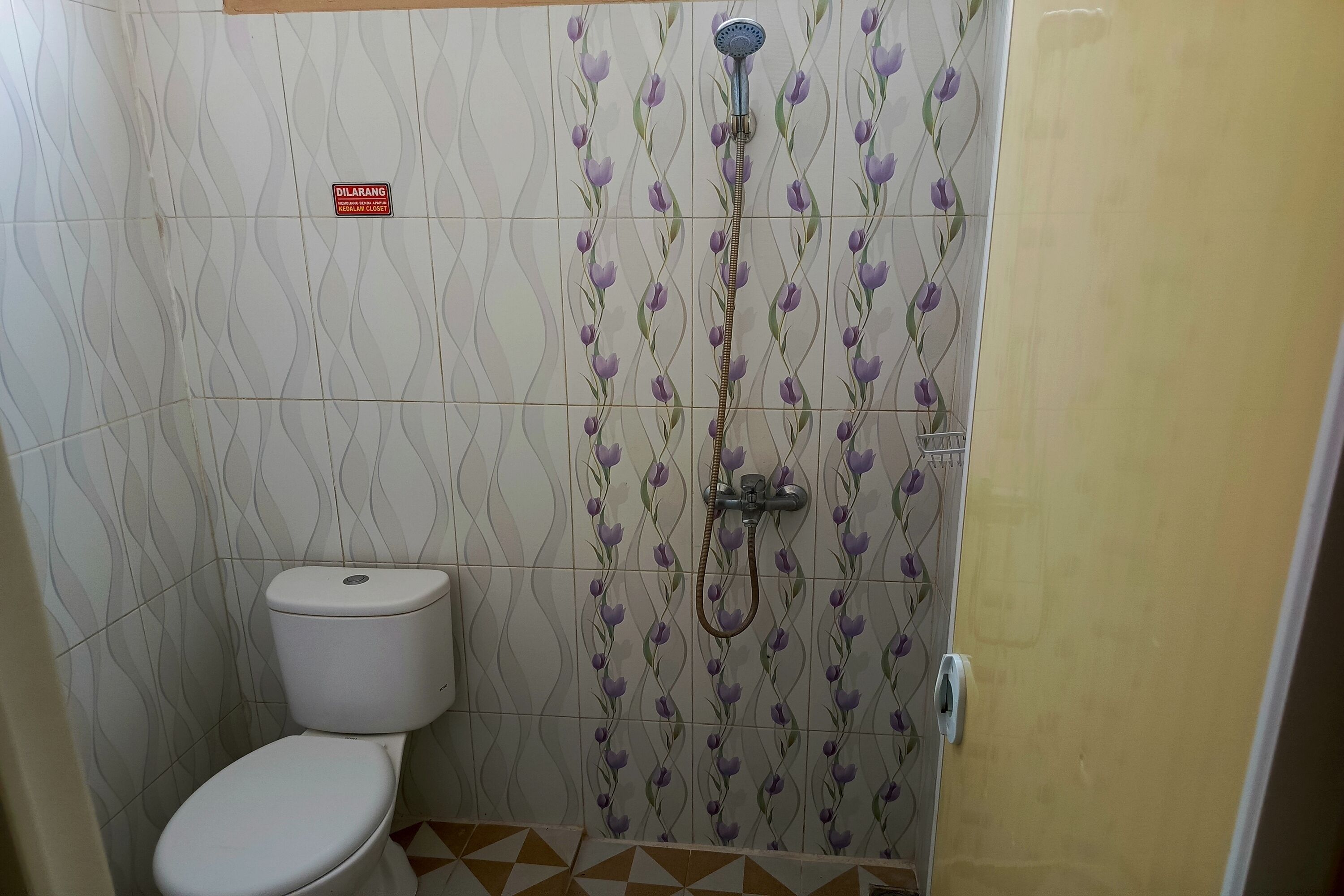 A bathroom with a toilet, shower, and patterned tiles.