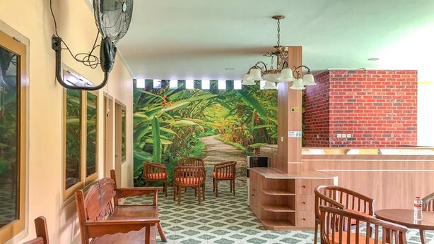 A room with a mural of a jungle path, wooden furniture, and a brick wall. - Adisa Homestay (Malang)
