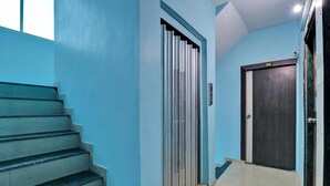 A staircase leading to a dark wooden door with a sign above it. - Hotel Alexa (Ahmedabad)
