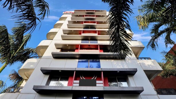 A modern hotel with a multi-story structure, balconies, and a clear view of the sky. - Hotel Alexa (Ahmedabad)