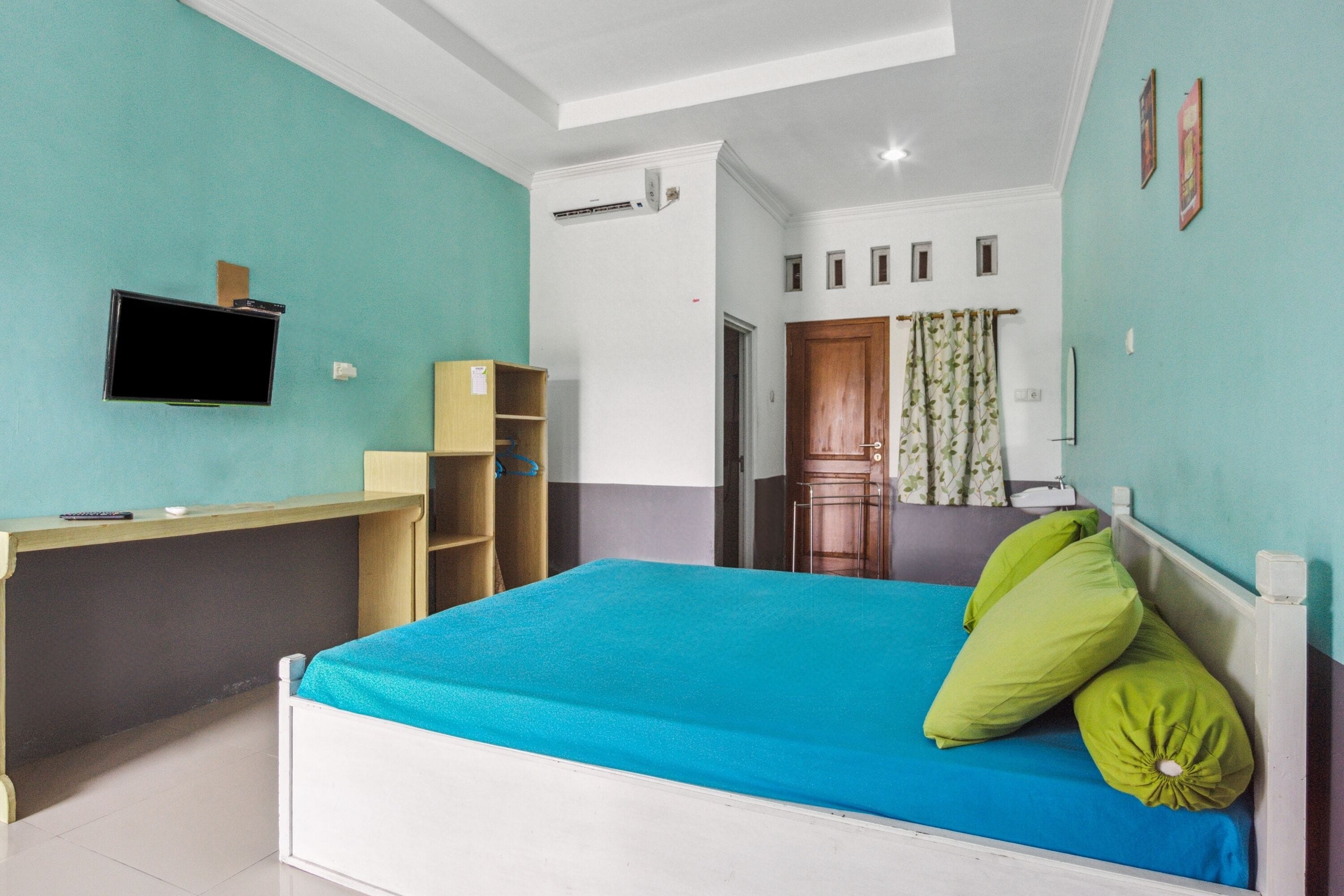 A bedroom with a bed, a desk, a TV, and a wardrobe.