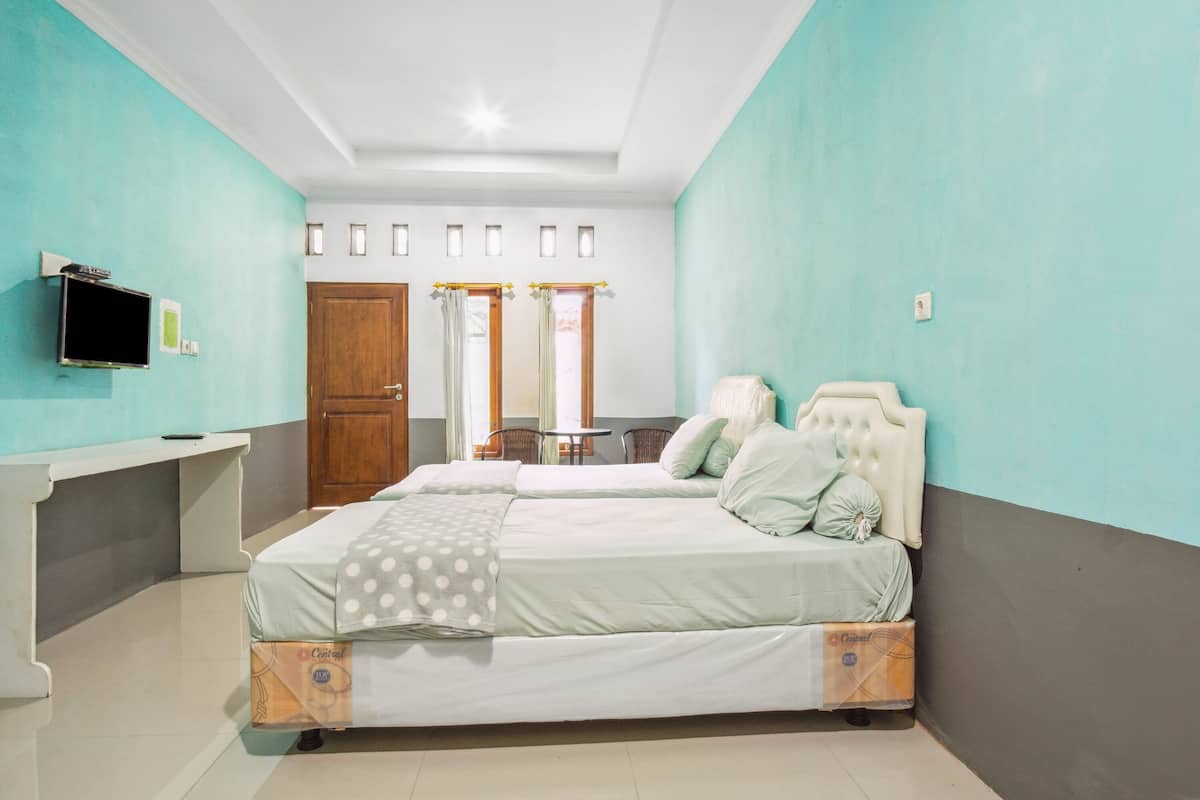 Une chambre à coucher avec un lit, une table de chevet, une télévision et une fenêtre avec des rideaux.