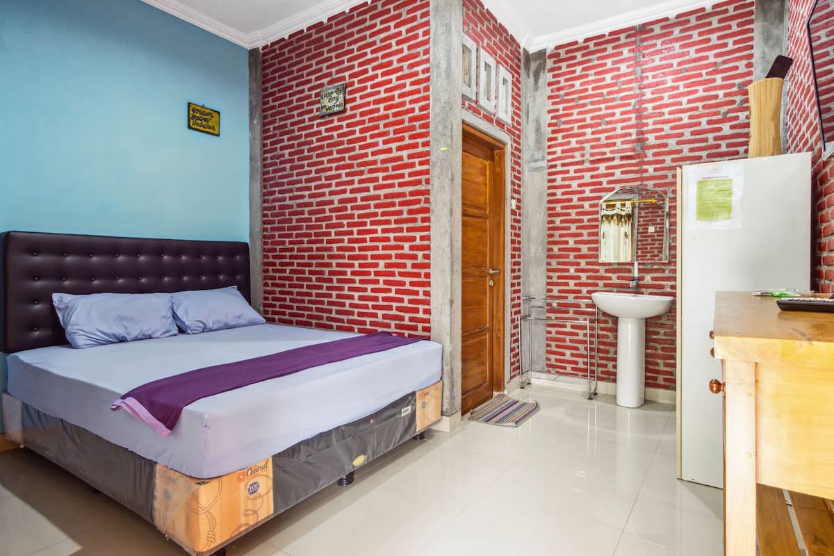 Une chambre à coucher avec un lit, une porte en bois, un lavabo et un réfrigérateur.