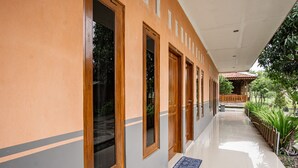 Un pasillo con puertas y ventanas de madera, suelo de baldosas y un tapete pequeño.