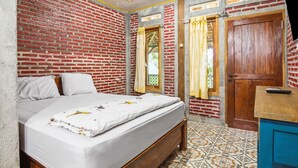 Un dormitorio con pared de ladrillo, cama de madera, aparador azul y baldosas de suelo estampadas.