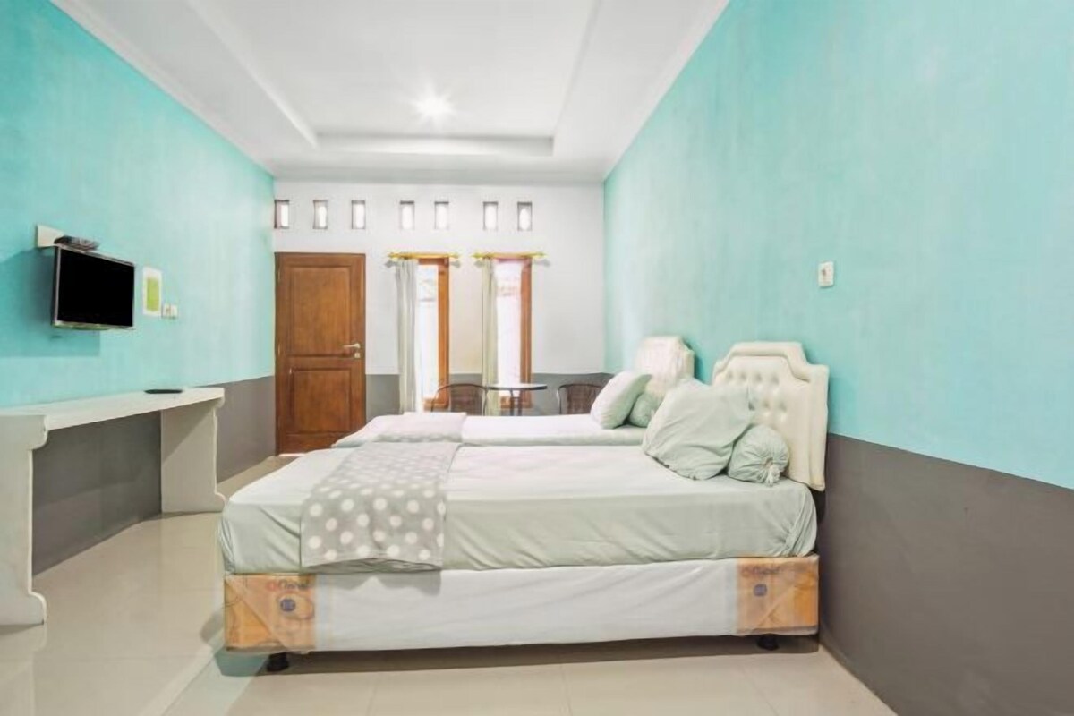 Quarto com duas camas, televisão, escrivaninha e porta.