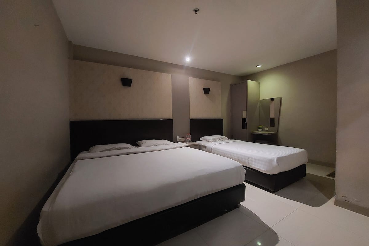 Ein Hotelzimmer mit zwei Betten, einem großen Spiegel und einem kleinen Tisch mit Pflanze.