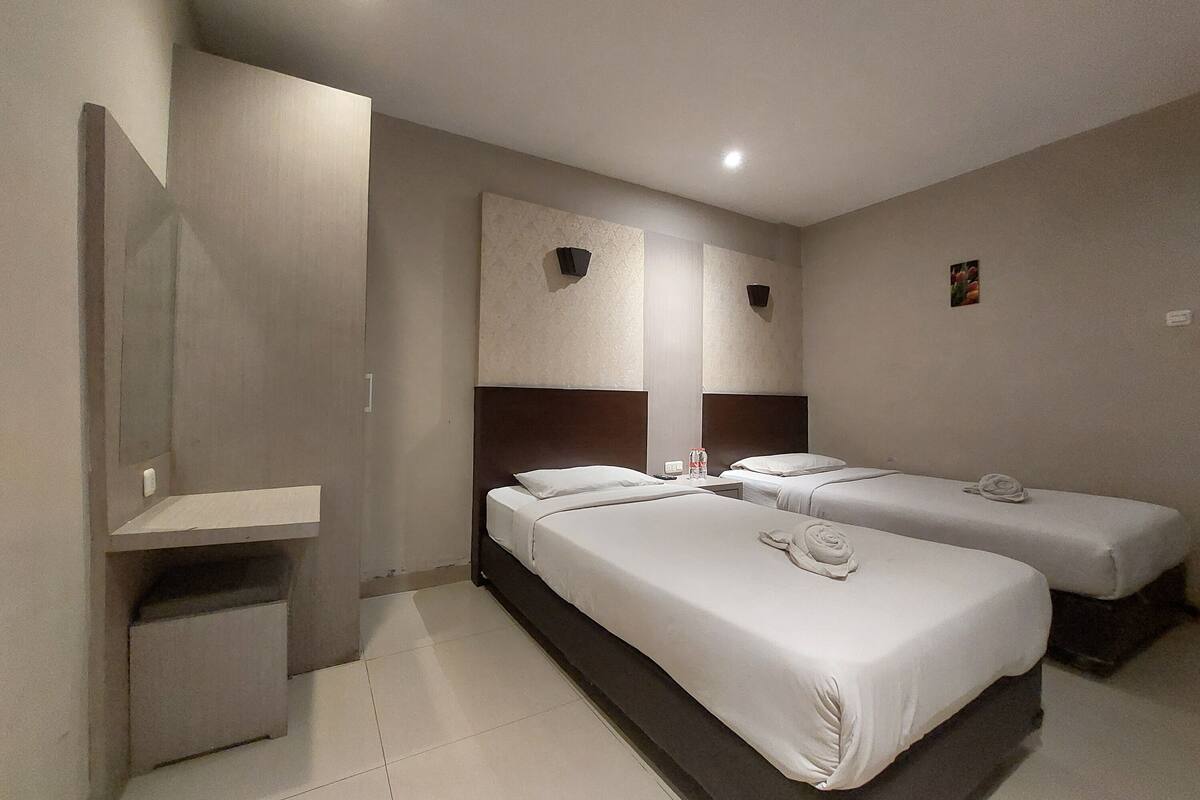 Ein Hotelzimmer mit zwei Betten, einem kleinen Schreibtisch und einem Spiegel.