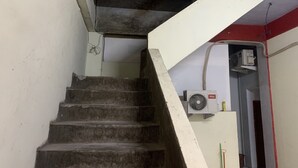A staircase with a white handrail and a fan mounted on the wall. - Mozza Guest House (Klaten)