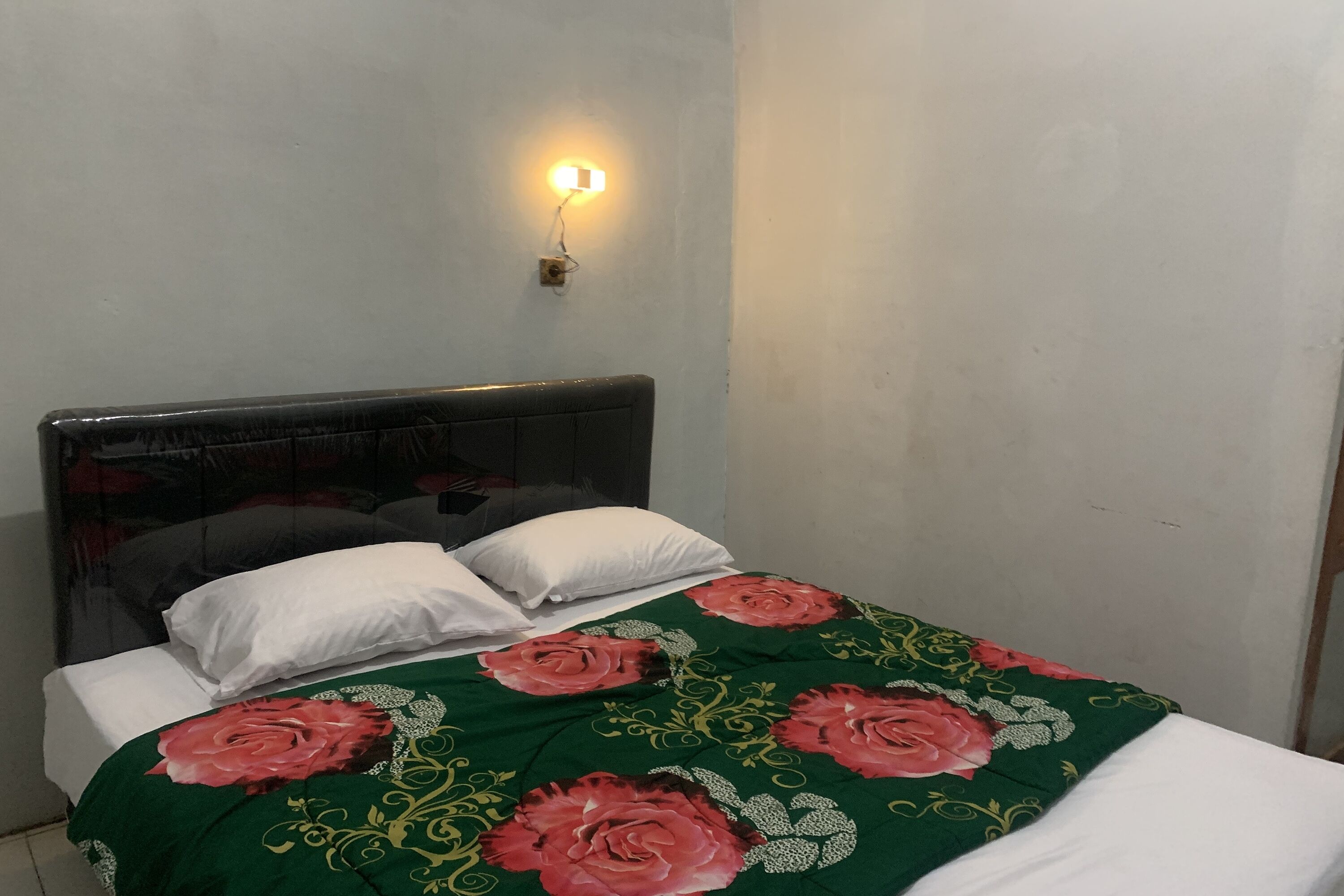 A bed with a green floral bedspread, white pillows, and a headboard.