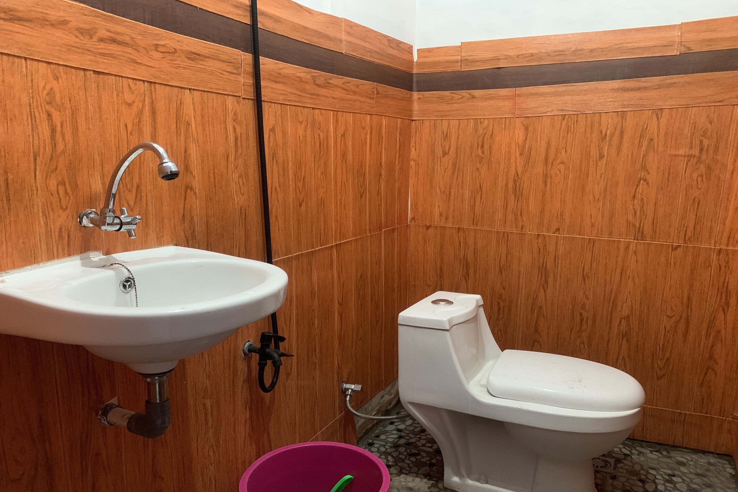 A bathroom with wooden paneling, a white sink, and a toilet.