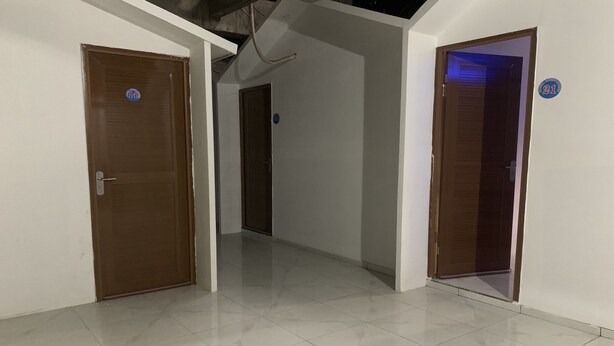 A corridor with three doors, each marked with a number. The corridor has a tiled floor and white walls. - Mozza Guest House (Klaten)