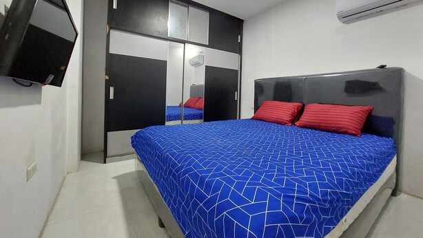 A bedroom with a bed, a wardrobe, a television, and an air conditioner. - Residence Syariah (Binjai)
