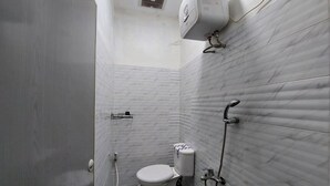 A small, compact bathroom with a toilet, a shower, and a wall-mounted air conditioning unit. - Residence Syariah (Binjai)