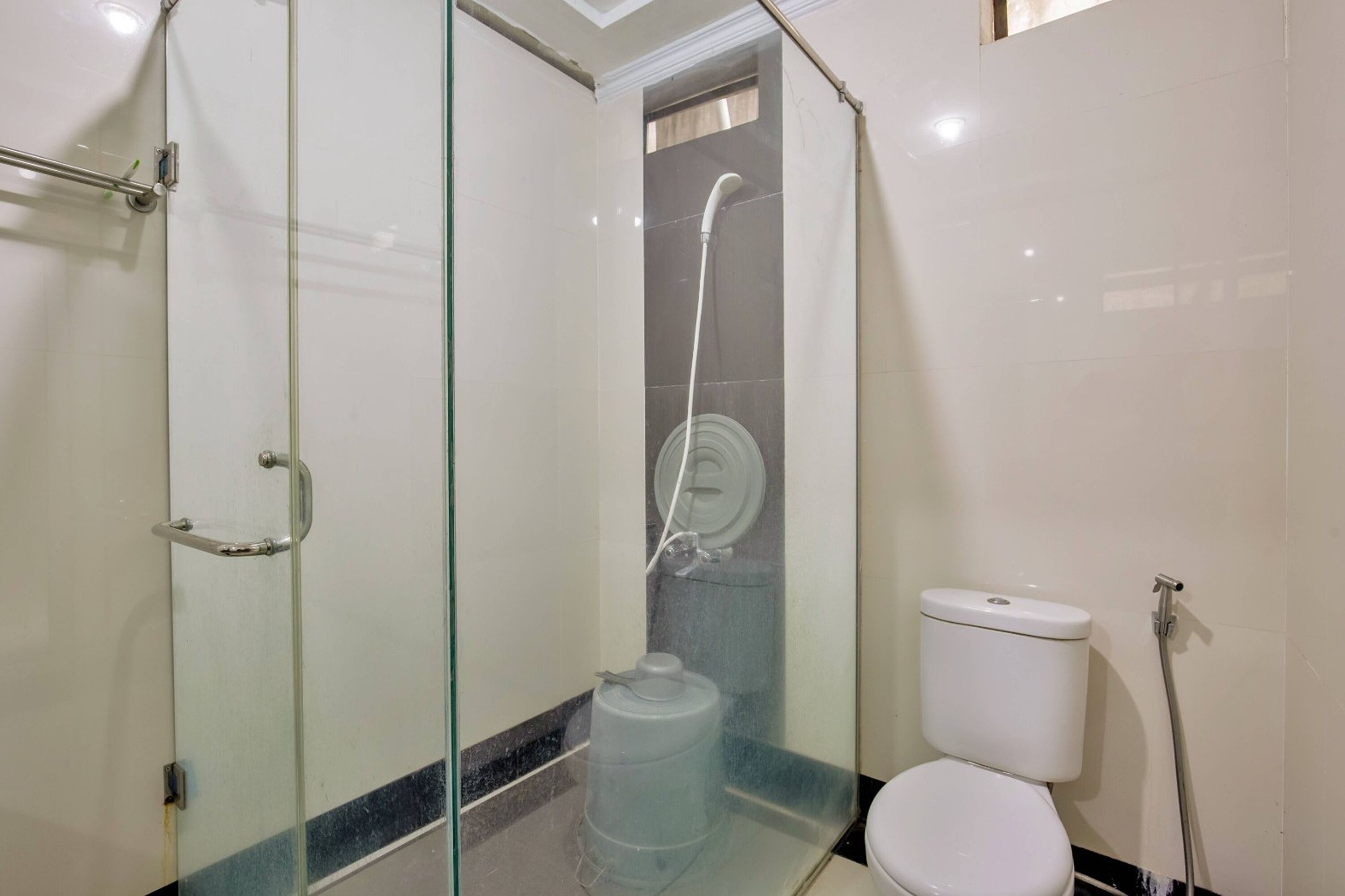 A bathroom with a glass-enclosed shower, a toilet, and a large water dispenser.