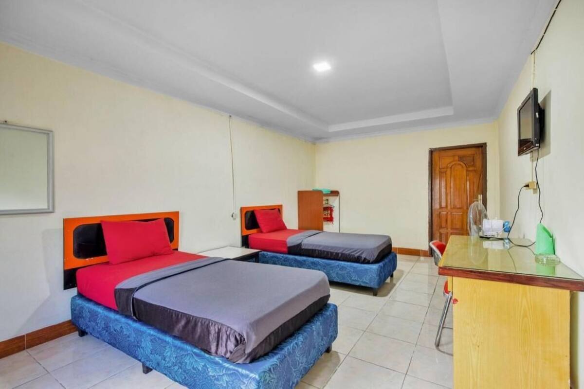 A room with two beds, a desk, a television, and a door.