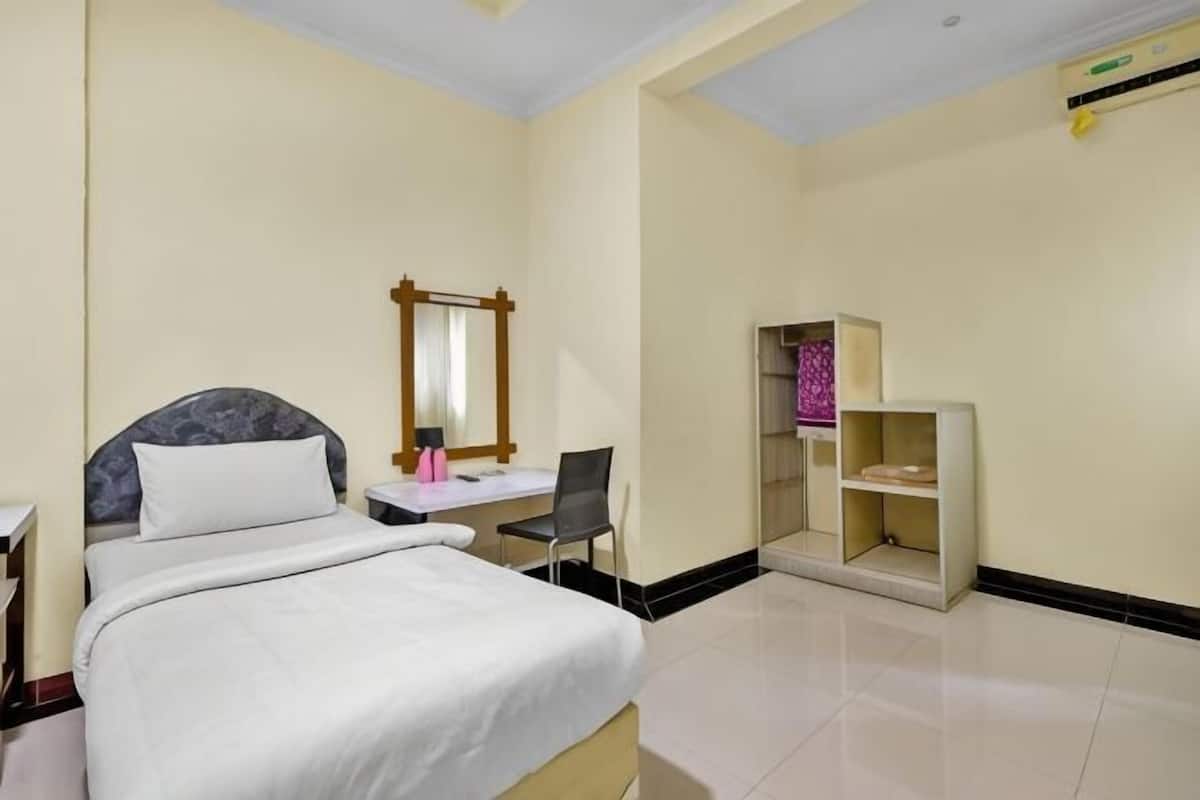 Une chambre d’hôtel comprenant un lit, un bureau, une chaise, un miroir et une petite étagère.