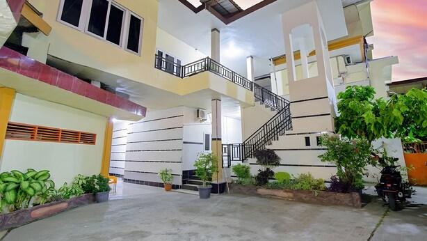 Un edificio residencial de varios pisos con una escalera central, balcones y plantas en macetas.