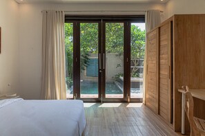 Ein Schlafzimmer mit einem Bett, einem Holzschrank und einer Schiebetür zu einem Poolbereich.