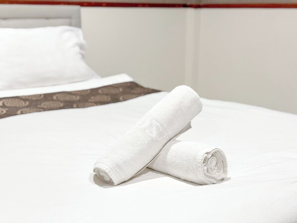 A neatly made bed with white linens and a patterned bedspread.