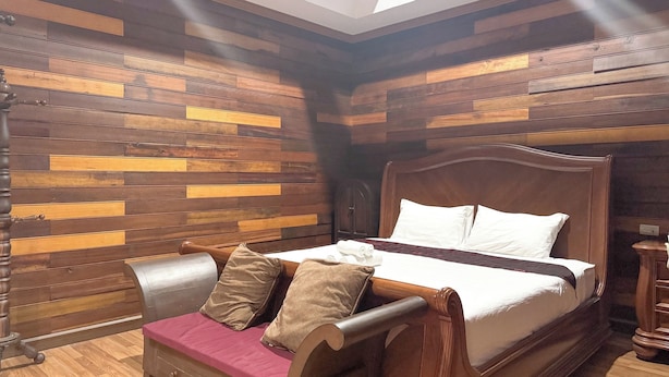 Une chambre avec un lit en bois, un banc agrémenté de coussins et un plafond en pente doté de fenêtres de toit.