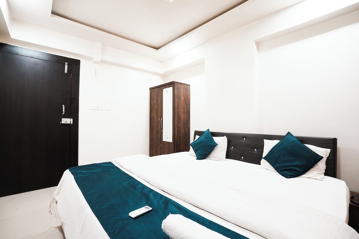 A hotel room with a bed, a wardrobe, and a nightstand.