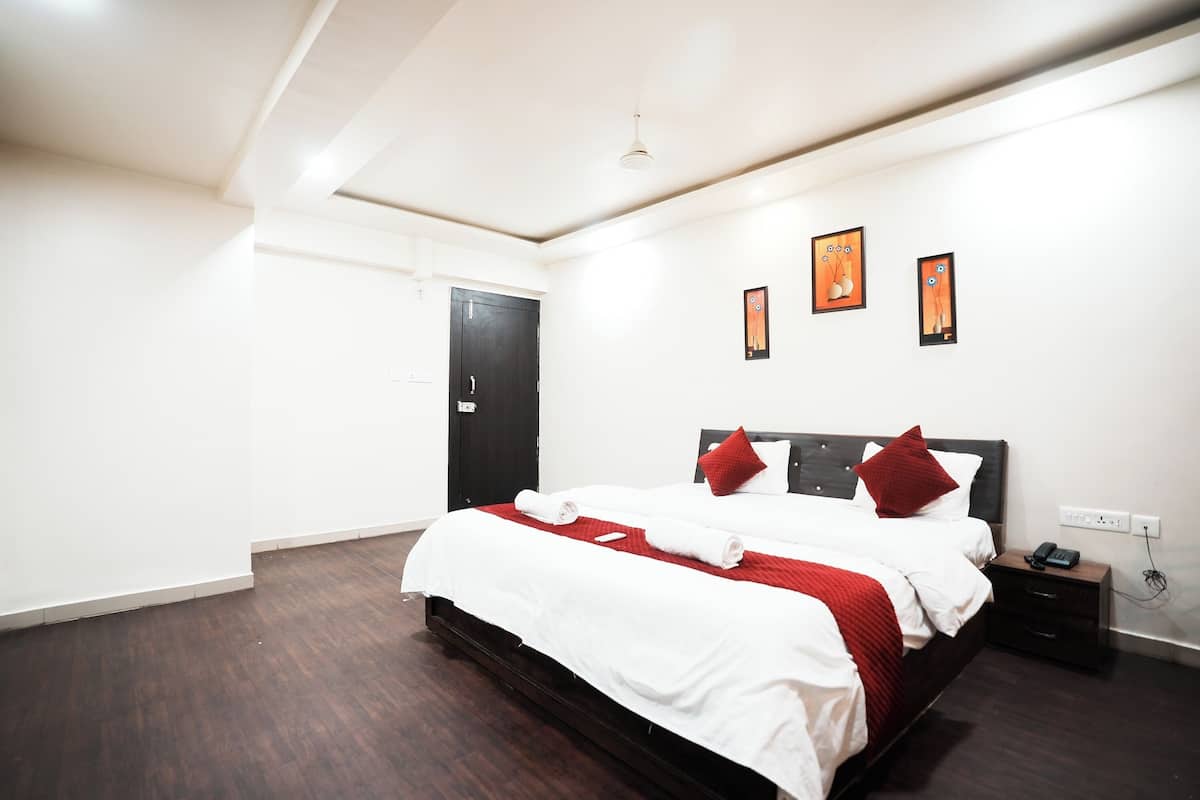 A hotel room with a large bed, a bedside table, a nightstand, and a wall-mounted phone.