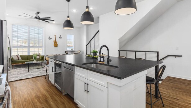A modern kitchen with a central island, pendant lighting, and a staircase leading to an upper level.