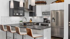 A modern kitchen with a central island, stainless steel appliances, and bar stools.