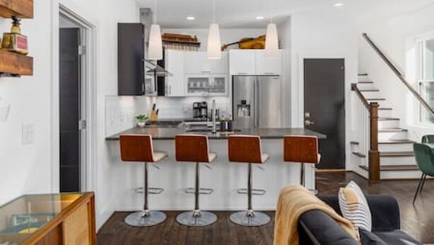 A modern kitchen with a central island, bar stools, and pendant lighting.