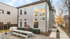 Un bâtiment moderne doté d’un patio comprenant une table de pique-nique et un petit jardin.