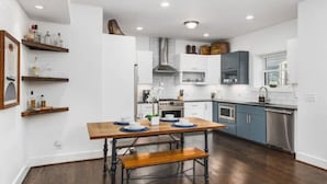 Une cuisine moderne avec un plancher en bois, des murs blancs et des appareils électroménagers intégrés.