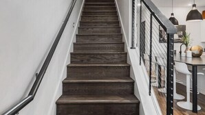 Una escalera con escalones de madera oscura y barandilla de metal negro.