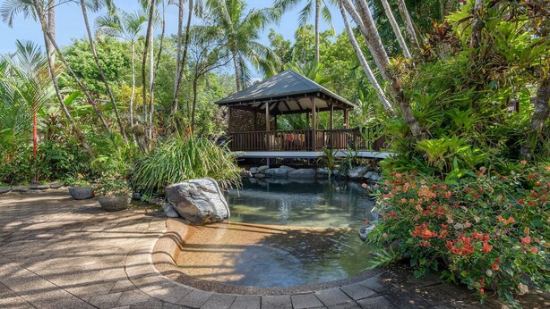 A tranquil garden with a pond, a wooden gazebo, and lush tropical vegetation. - A Tropical Treat @ Sea Level / Port Douglas (PORT DOUGLAS)