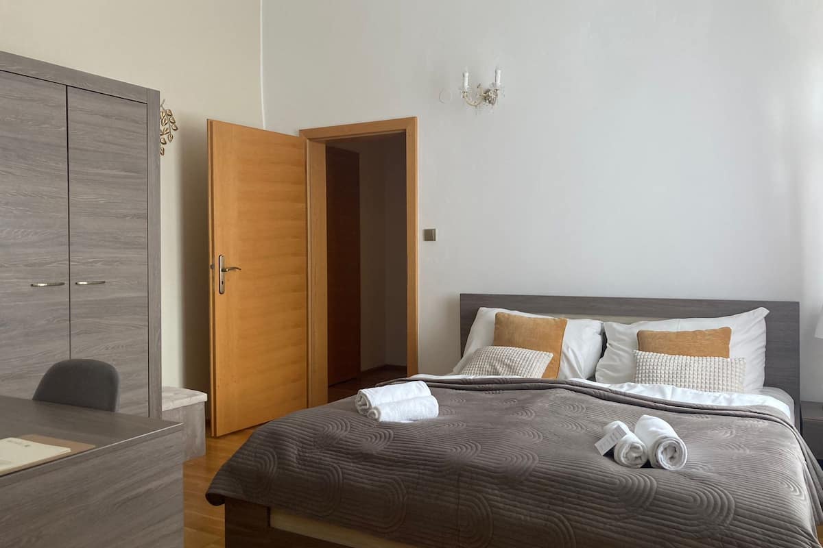 A bedroom with a bed, a desk, and a wardrobe.