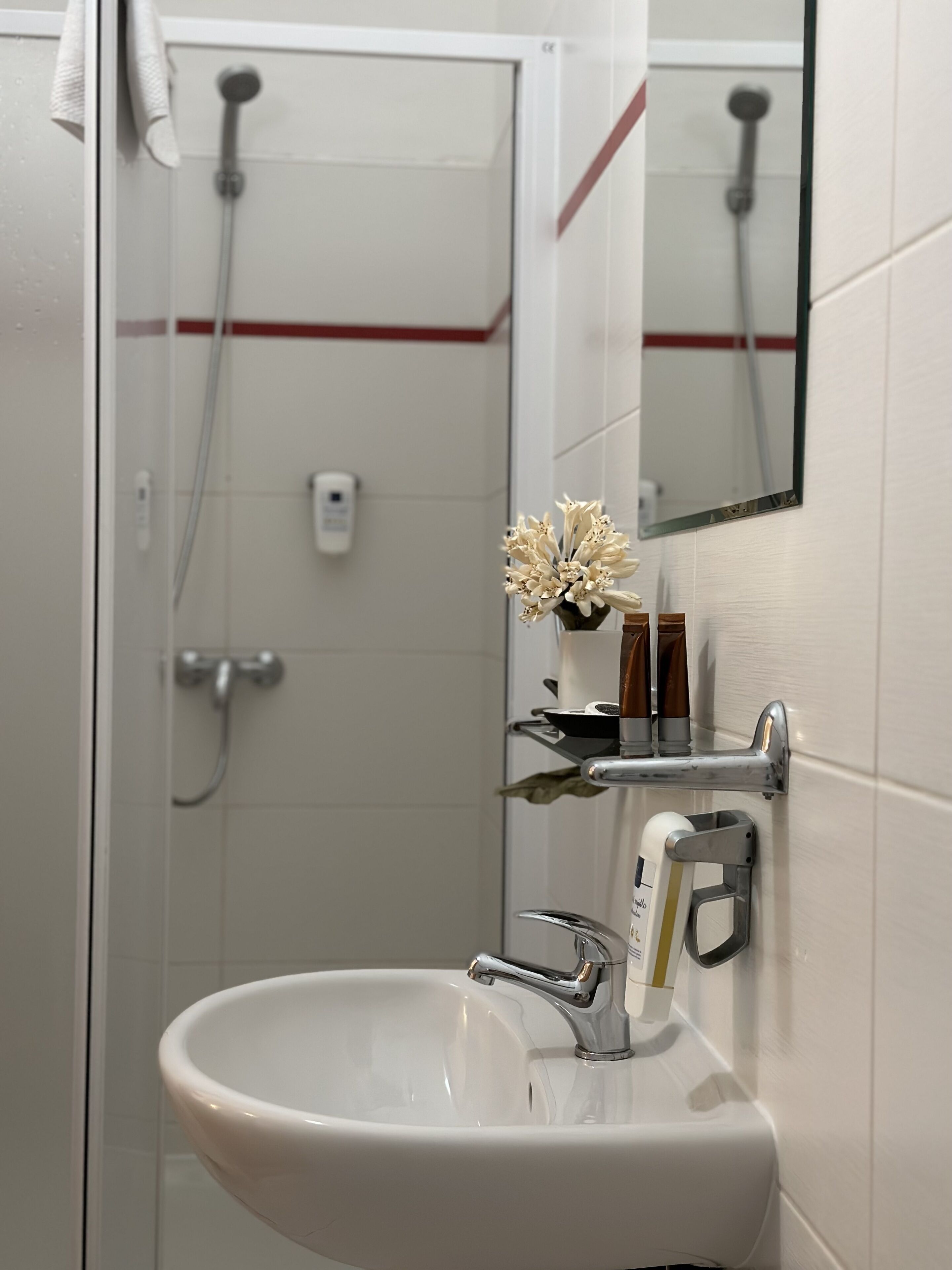 Ein Badezimmer mit einem weißen Waschbecken, einem Spiegel und einer Dusche.