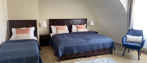 A hotel room with two beds, a blue chair, a patterned rug, and a curved ceiling.