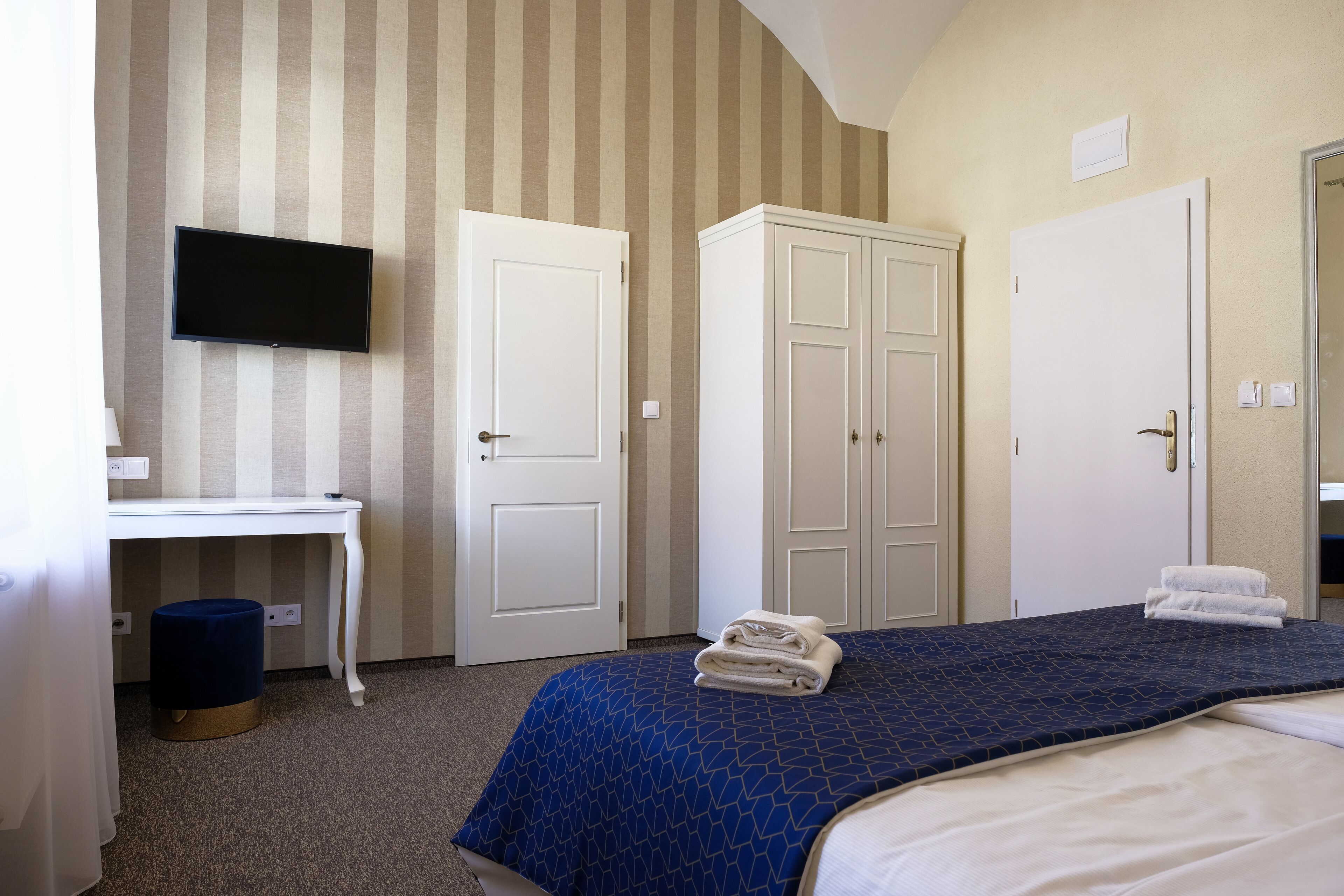 A hotel room with a bed, a desk, a television, and two wardrobes.