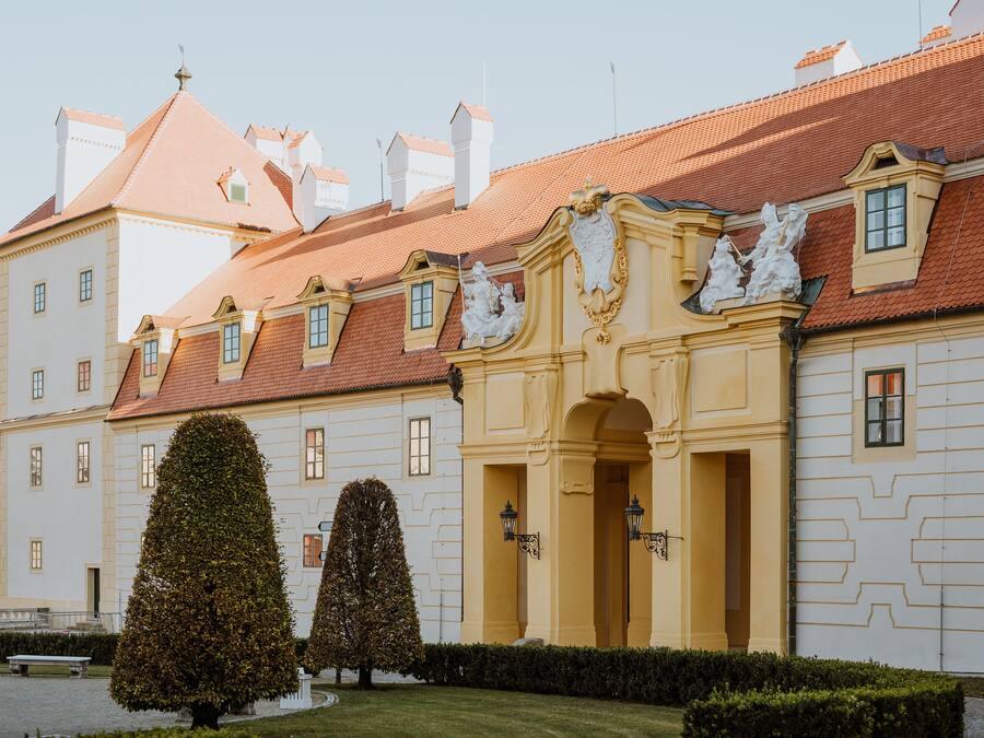 Un edificio histórico con fachada simétrica, múltiples ventanas y una entrada central adornada con detalles decorativos.